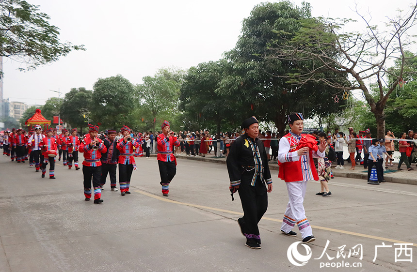 双方情意浓浓后，就进入谈婚论嫁阶段。在“非遗舞鹿接新娘”环节，壮族新郎一行带着彩礼走在迎亲路上，敲锣打鼓，热闹非凡。人民网记者 彭远贺摄